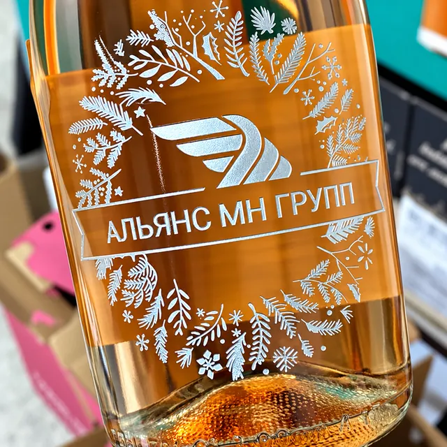 Крупный план серебряной пескоструйной гравировки на розовом игристом вине с логотипом компании